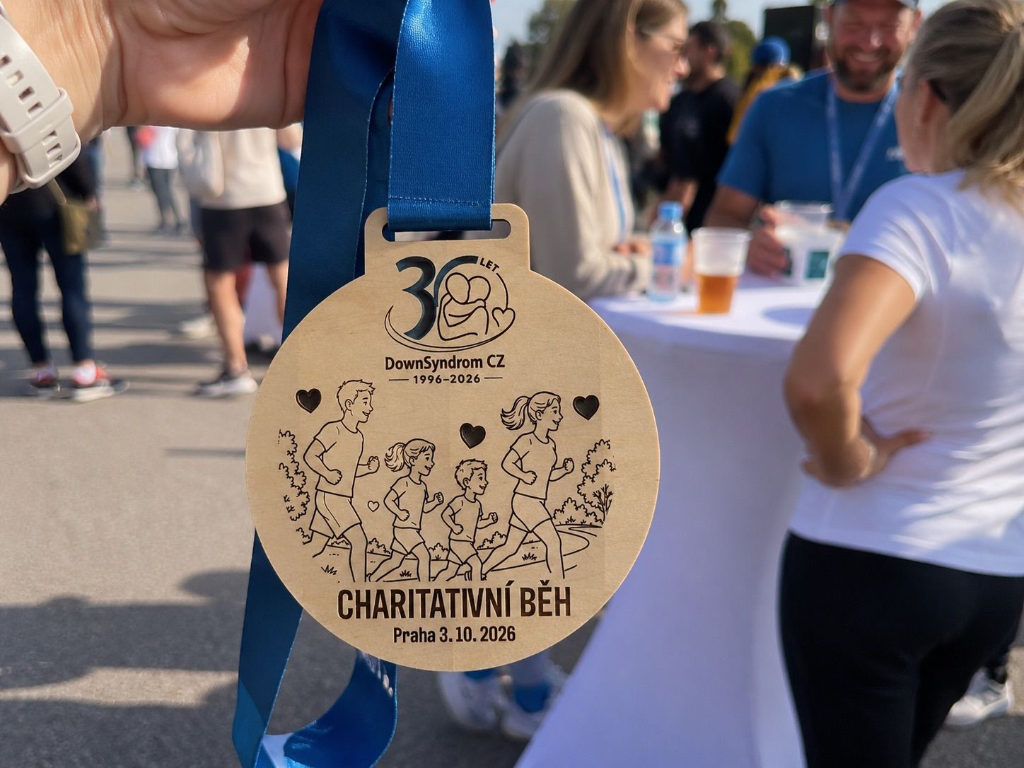 Charitativní běh s davem účastníků a dřevěnou medailí HOORAY